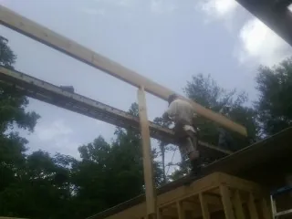 Carpenter setting a ridge beam over a new addition frame — Ice Dam Removal by Roofing Brothers in Pioneer