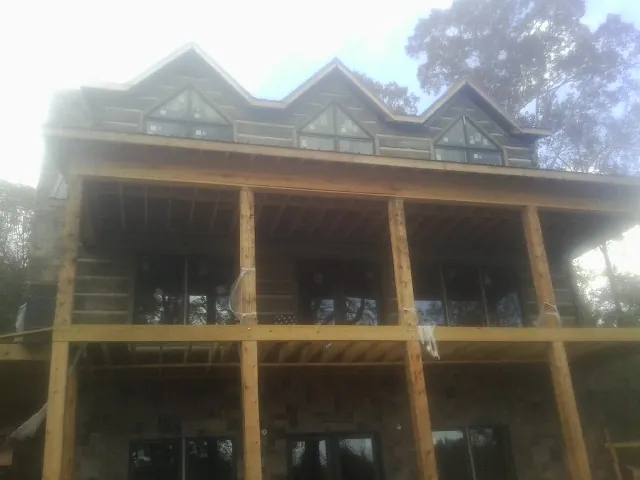 Dormers and porch framing on a large log home under construction — Roof Coating work by our crew in Pioneer