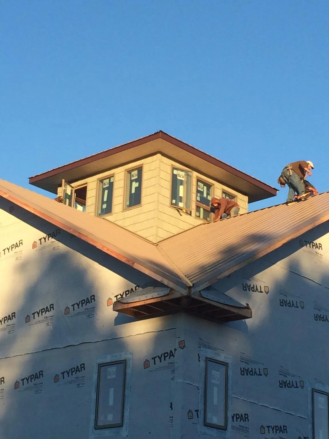 Roofers working around a rooftop cupola on a new metal roof at sunset — Roof Waterproofing in Pioneer by Roofing Brothers